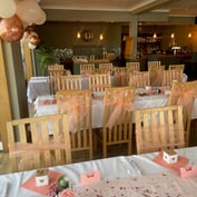A close-up of the banquet tables with rose-gold balloons, peach tulle and roses, with the bar in the background