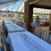 Long banquet tables set for a wedding breakfast in the sunlit conservatory