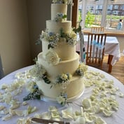 A five-tier white wedding cake with roses and gypsophila