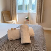 Folded towel and decorative shell on the bed, bay window beyond