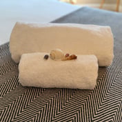 Two rolled white towels and decorative shell on a herringbone throw