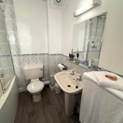Family room en-suite with bath, shower above, basin and a scallop-shell towel detail