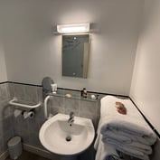 Garden room en-suite with grab rail, basin and scallop-shell towel detail