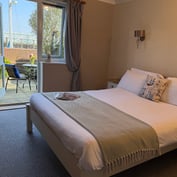 Ground-floor garden room with double bed and patio doors open onto a private patio