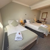Triple room from the door, single and double beds with a dressing-table mirror