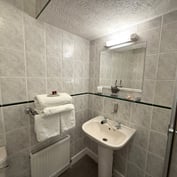 Triple room en-suite — tiled bathroom with walk-in shower, basin and towels on the radiator