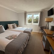 Twin room wider view with desk, chair, hospitality tray and bedside table