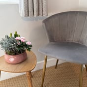 Grey velvet chair and side table with pink carnations in the twin room