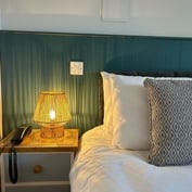 Wicker bedside lamp on a green panelled wall in the twin room