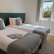Twin room with two single beds, green panelled headboard and a window onto the garden