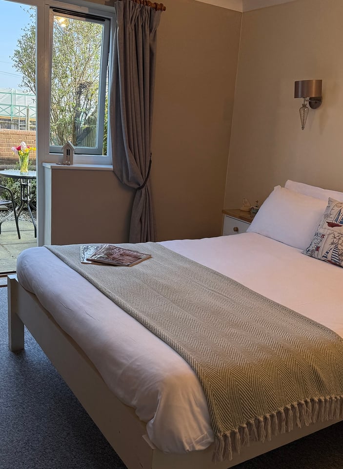 Ground-floor garden room with double bed and patio doors open onto a private patio