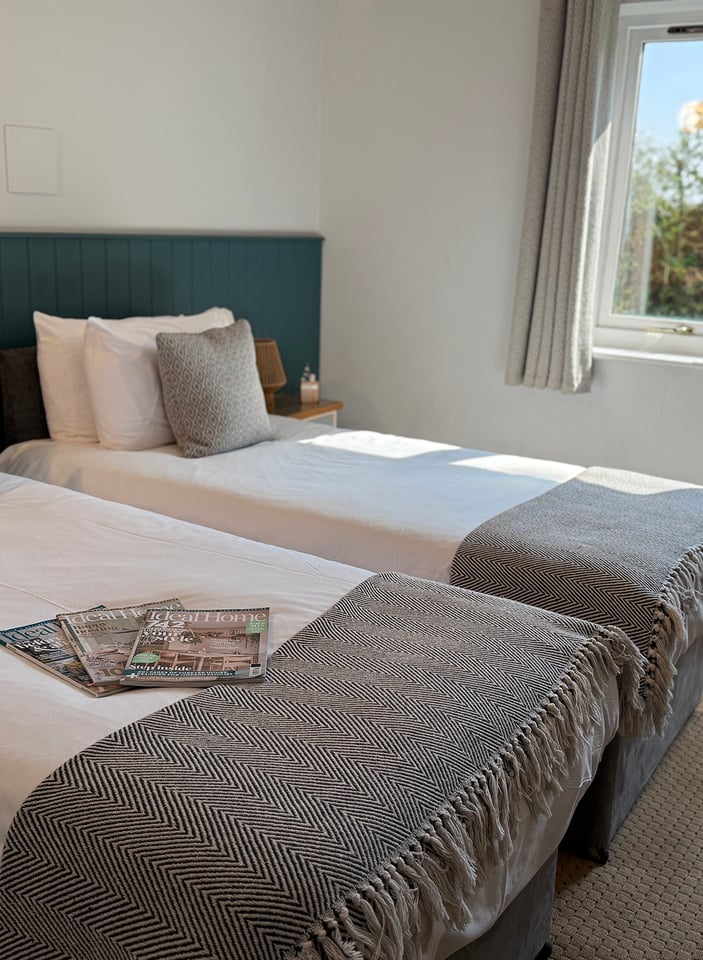 Twin room with two single beds, green panelled headboard and a window onto the garden